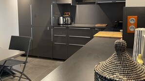 A modern kitchen with dark cabinetry, a built-in oven, and a flat-screen TV.