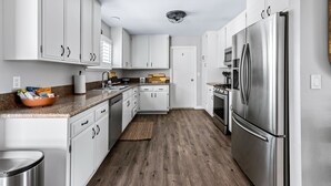 A modern kitchen with white cabinets, a stainless steel refrigerator, and a wooden floor. - Lucky Moon Retreat | JTree Oasis w/Hot Tub & Pool (Yucca Valley)