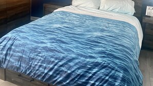 Ein Schlafzimmer mit Bett, Nachttisch, Wandheizung und Deckenventilator.