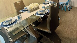 Ein Esszimmer mit einem Glastisch, blau-weißem Geschirr und einer Wanddekoration mit einem Seestern.