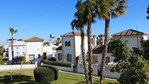 Zona residencial con edificios blancos, palmeras y un césped cuidado.