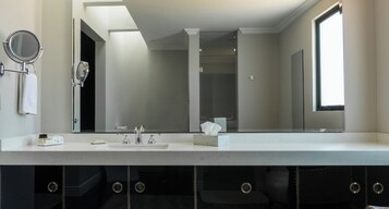 Un baño moderno con un espejo grande, un lavamanos y una ventana.