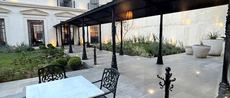 Un patio al aire libre con una mesa y sillas, un pérgola y un edificio al fondo.