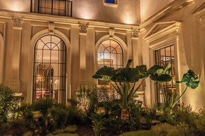 Une cour d’hôtel dotée de grandes fenêtres en arc de cercle, d’une plante centrale et d’un jardin bien entretenu.