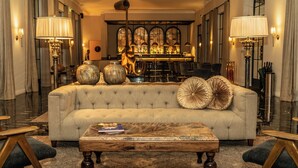Un elegante salón con un sofá capitonado, una mesa de centro de madera y dos lámparas.
