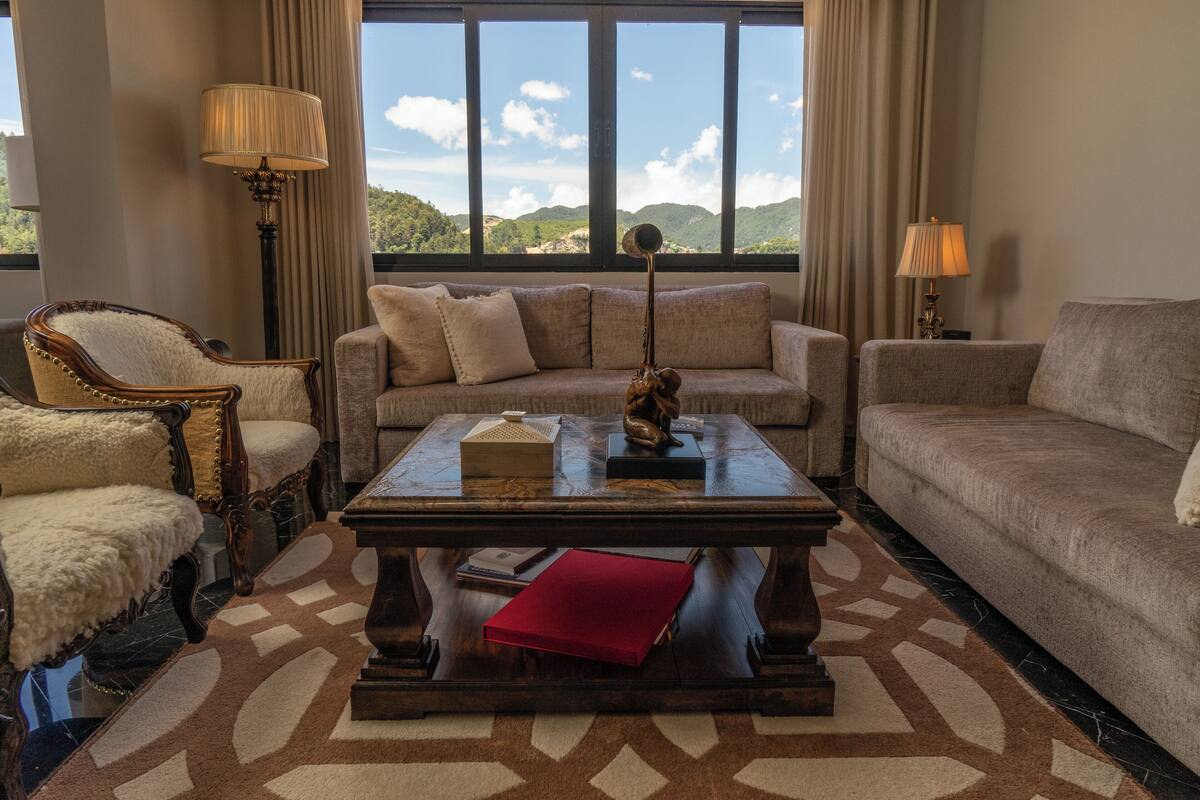 A room with a sofa, armchair, and a coffee table with decorative items.