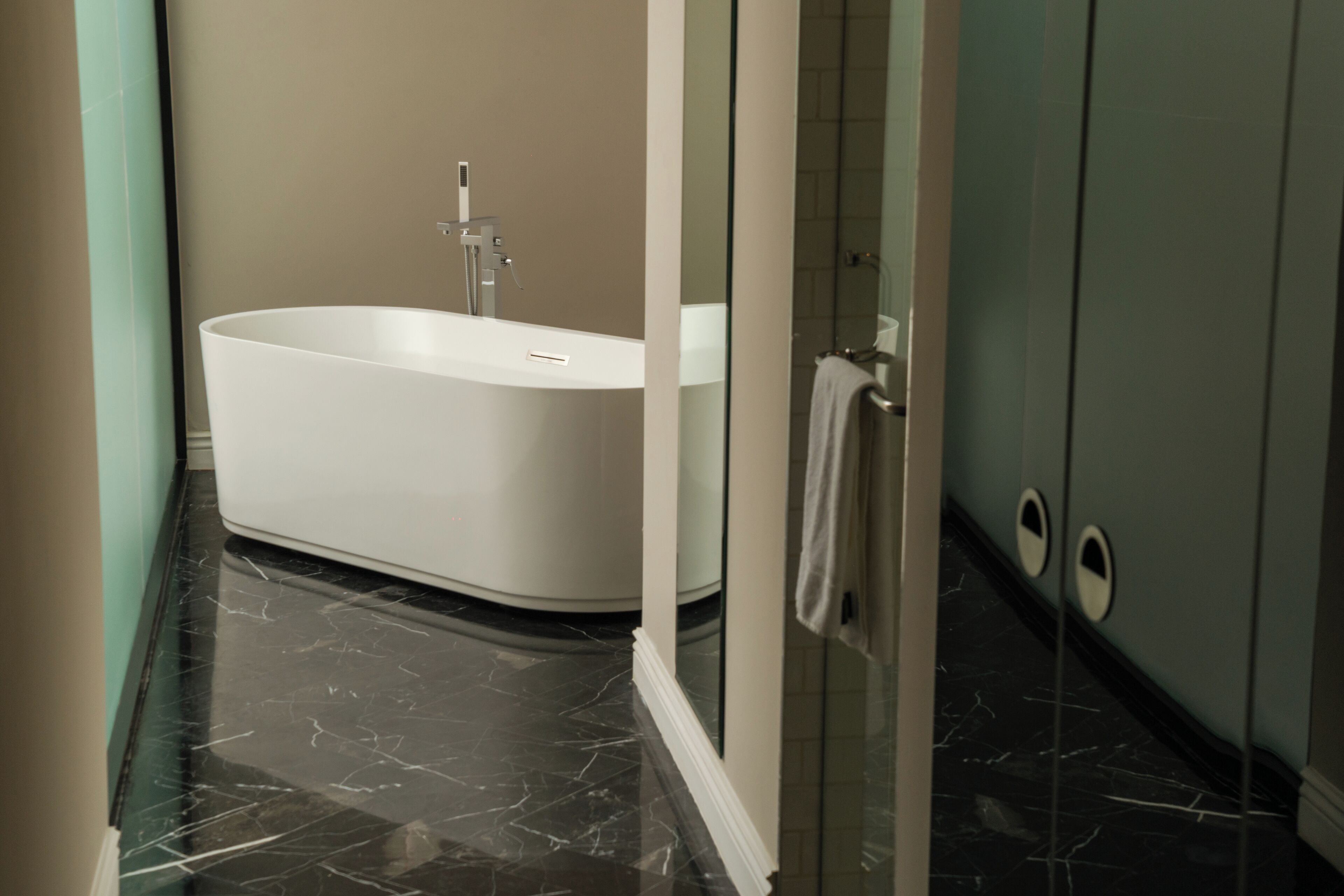 Ein modernes Badezimmer mit einer freistehenden Badewanne, einer Duschkabine aus Glas und einem Marmorboden.