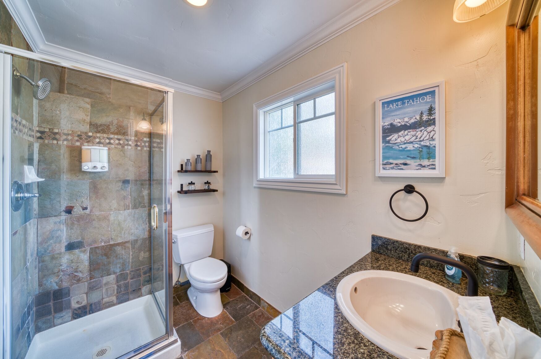 Une salle de bain avec une douche à parois de verre, des toilettes, un lavabo et une fenêtre.