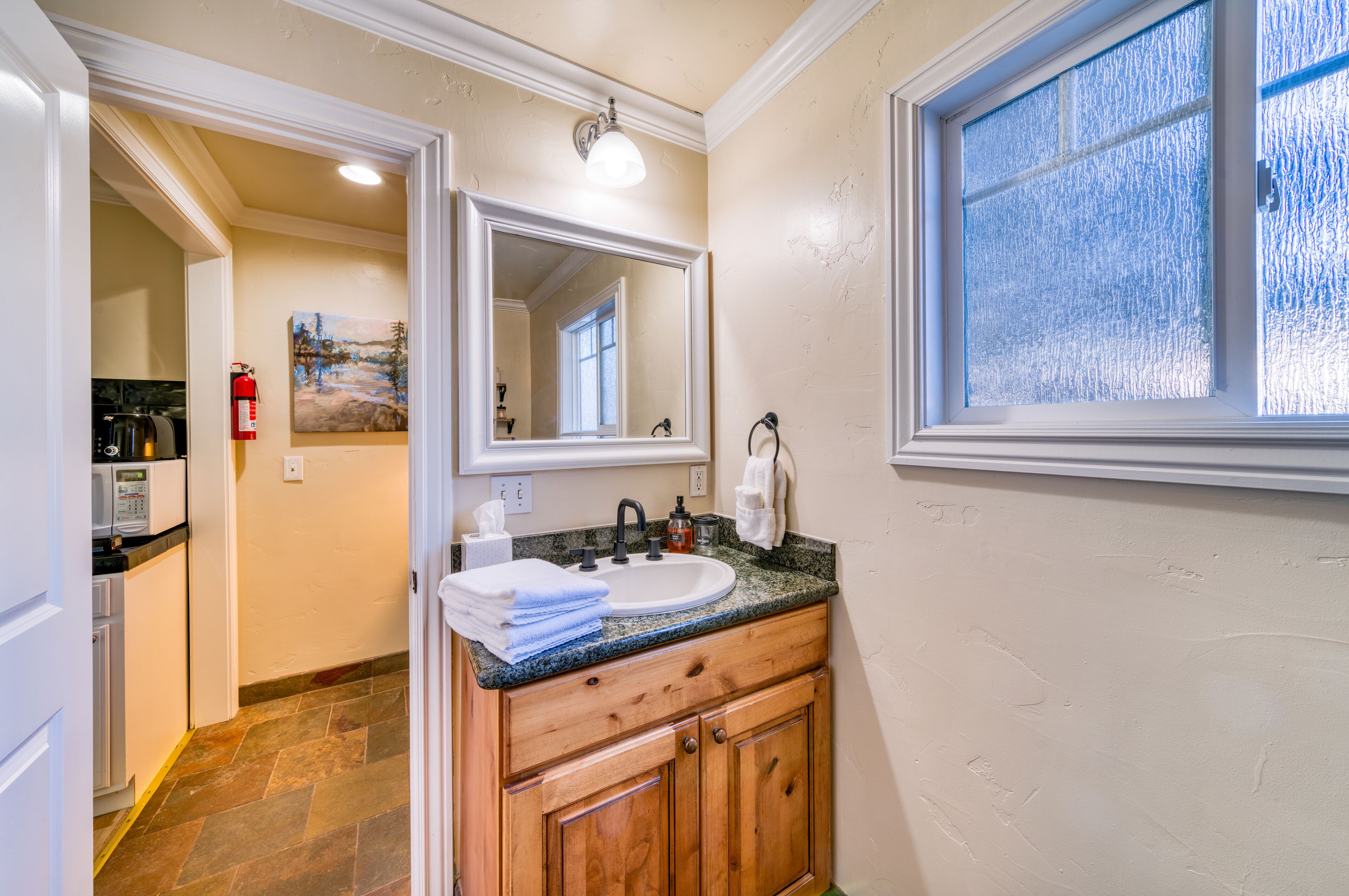 A bathroom with a sink, mirror, and window.
