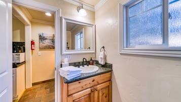 A bathroom with a sink, mirror, and window.
