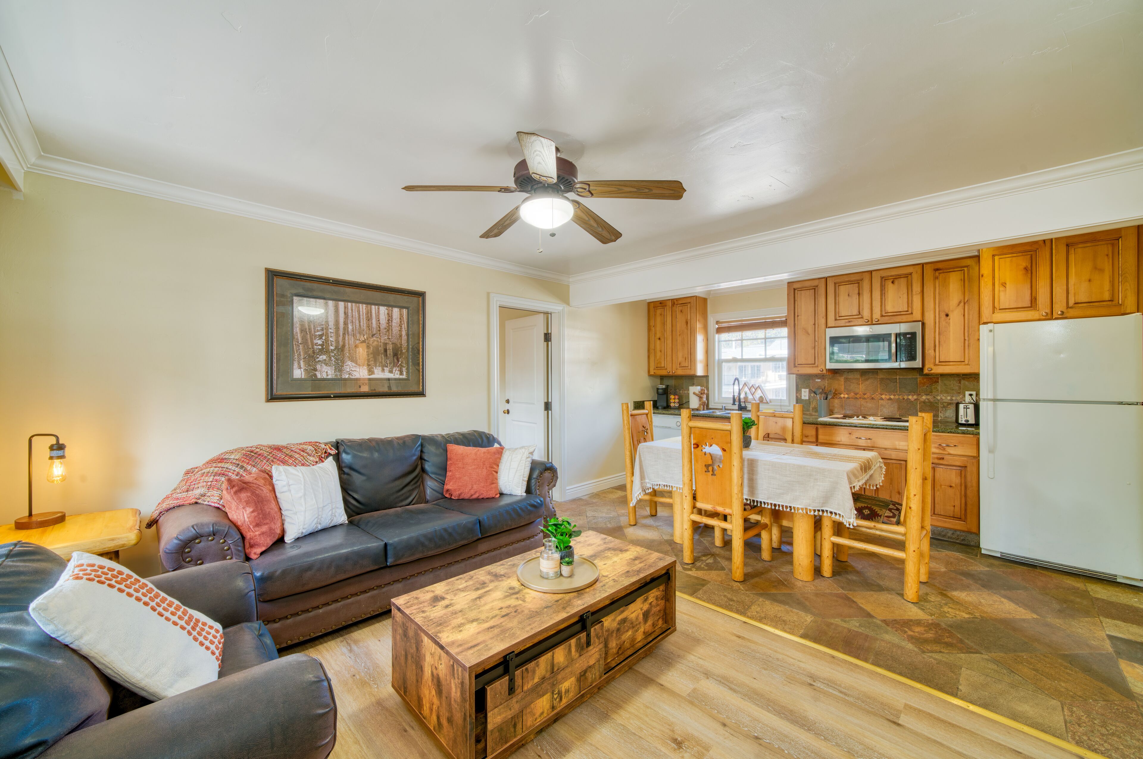 A living room with a dark leather sofa, a wooden coffee table, and a ceiling fan.
