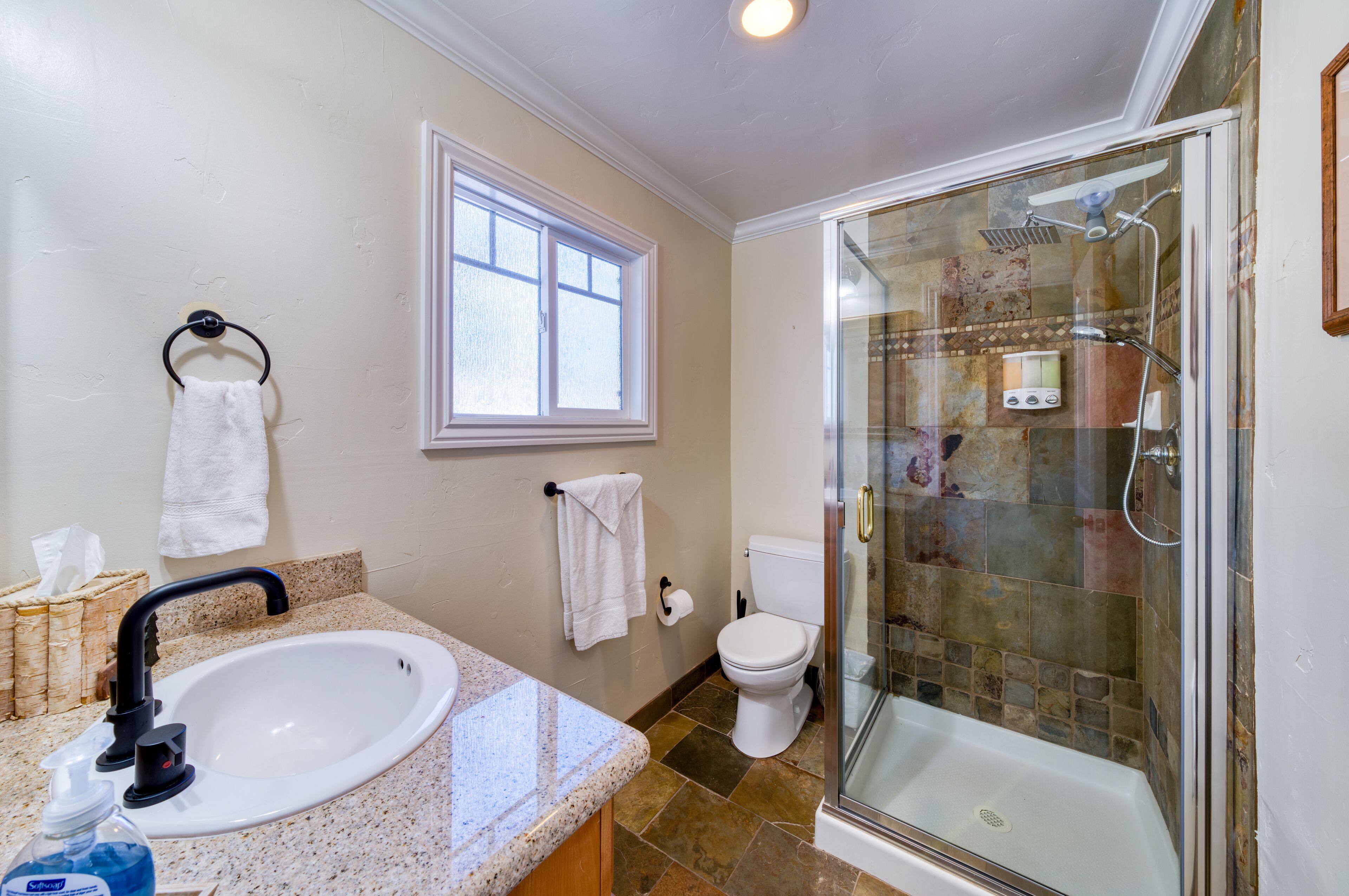 A bathroom with a sink, toilet, and glass-enclosed shower.