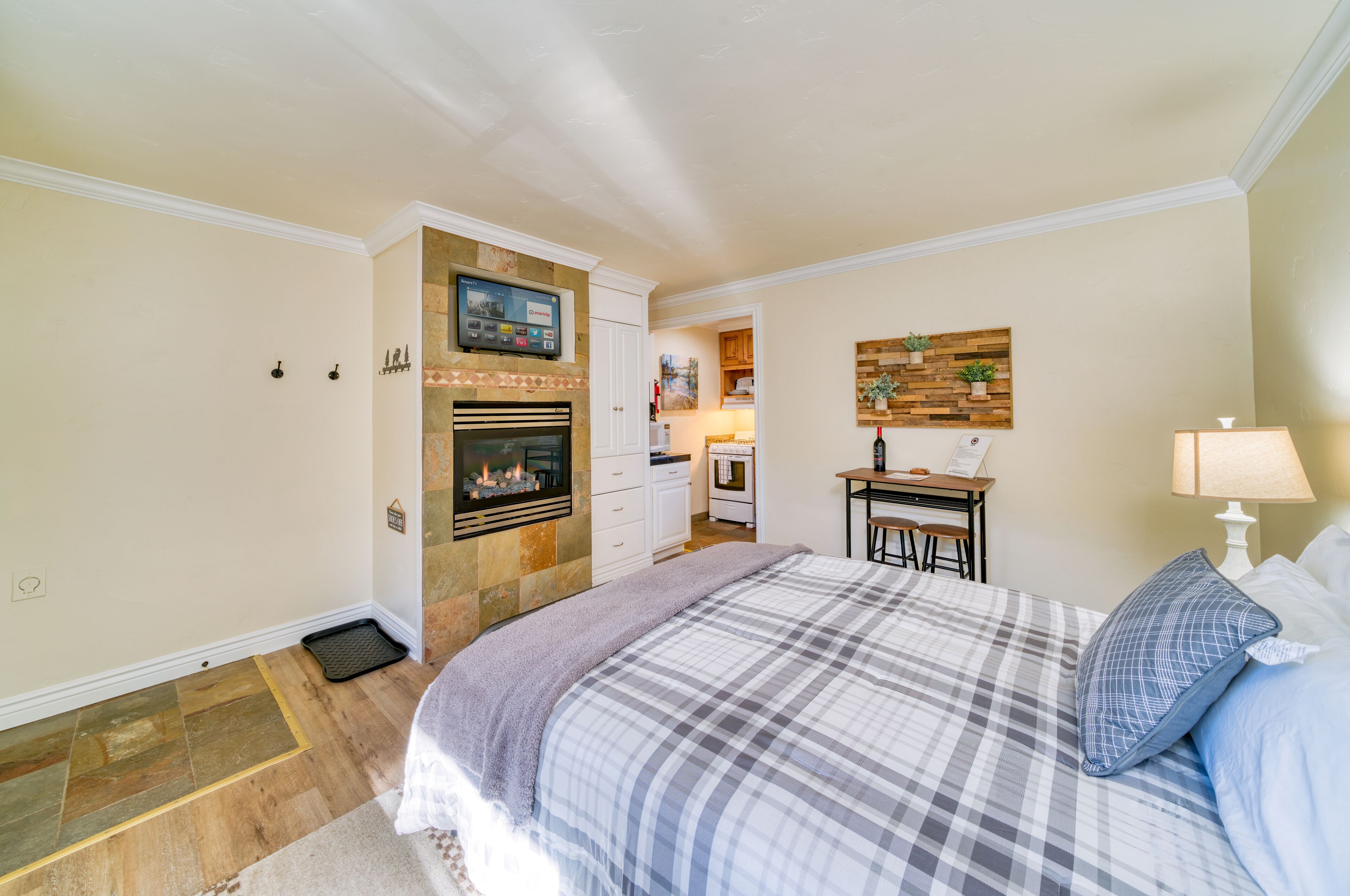 A bedroom with a fireplace, a desk with a chair, and a bed with a plaid bedspread.