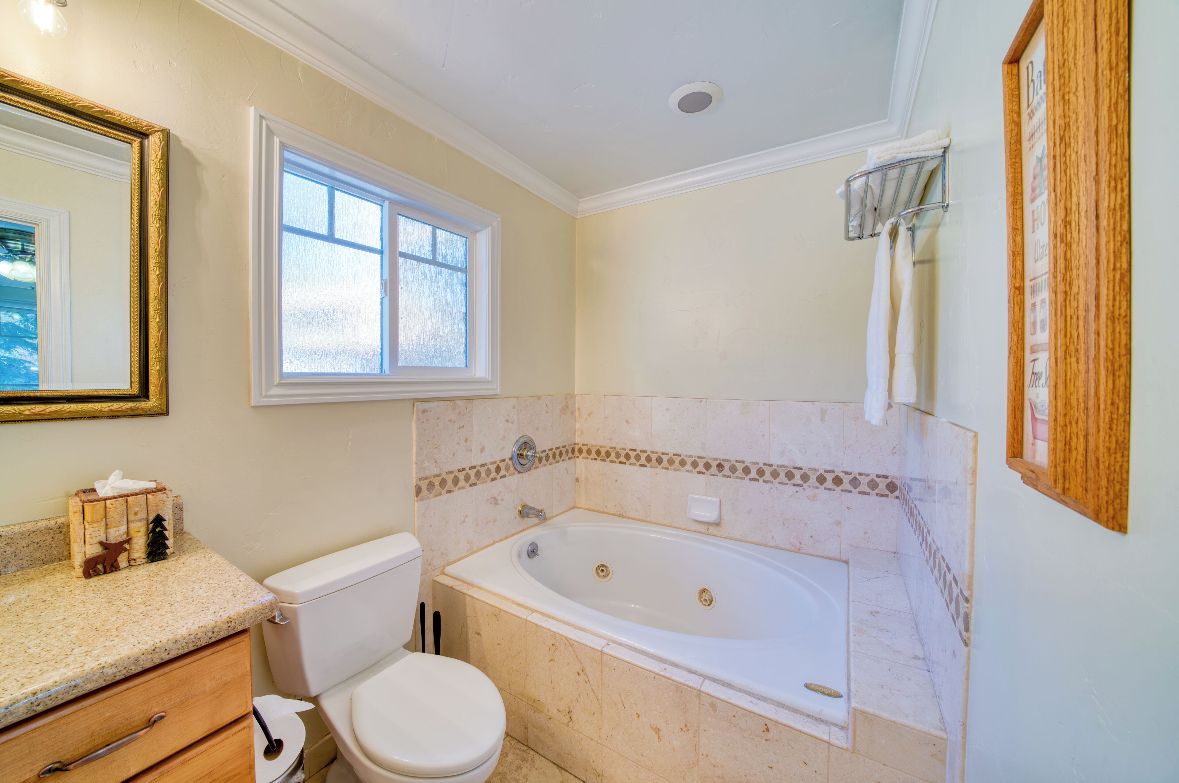 A bathroom with a toilet, sink, bathtub, and a window.
