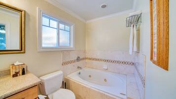 A bathroom with a toilet, sink, bathtub, and a window.