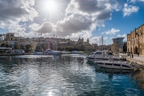 A marina with boats docked, a clear sky, and buildings in the background.