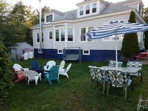 Relax in the serene backyard with a patio table, comfortable seating, and a shaded area under a large umbrella.