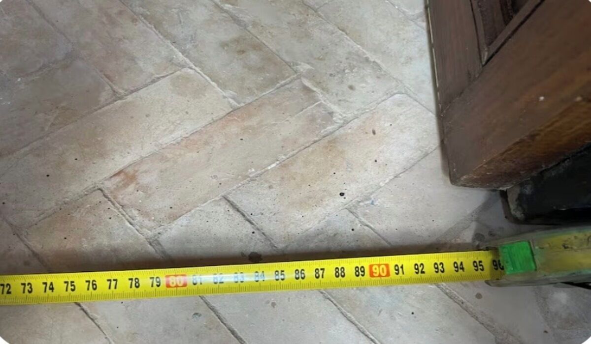 Un ruban à mesurer jaune est posé sur un sol carrelé, et il sert à mesurer une distance de 90 centimètres.