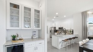A modern kitchen with white cabinets, a central island with bar stools, a built-in oven, and a refrigerator. - ☀ Bike to Ritz & Beaches, 3 Kings, 2 Masters, Easy, Bikes, Heated Pool ☀ (Naples)