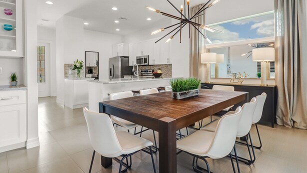 A modern kitchen with white cabinetry, a central island, and a dining area with a wooden table and white chairs. - ☀ Bike to Ritz & Beaches, 3 Kings, 2 Masters, Easy, Bikes, Heated Pool ☀ (Naples)