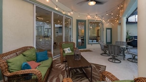 An outdoor patio with wicker furniture, string lights, and a ceiling fan. - 4 BR House w/ heat-pump pool! (Dunnellon)