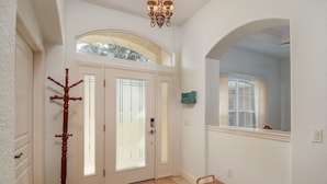 A hallway with a wooden bench, a coat rack, and a door with frosted glass panels. - 4 BR House w/ heat-pump pool! (Dunnellon)