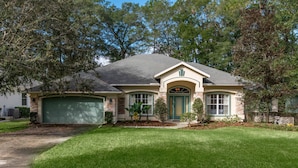 A single-story house with a garage, a front porch, and a well-maintained lawn. - 4 BR House w/ heat-pump pool! (Dunnellon)