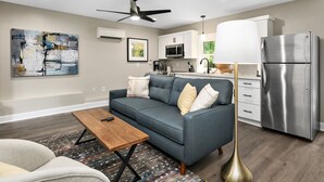 Ein modernes Wohnzimmer mit einem grauen Sofa, einem Holztisch und einer Stehlampe.