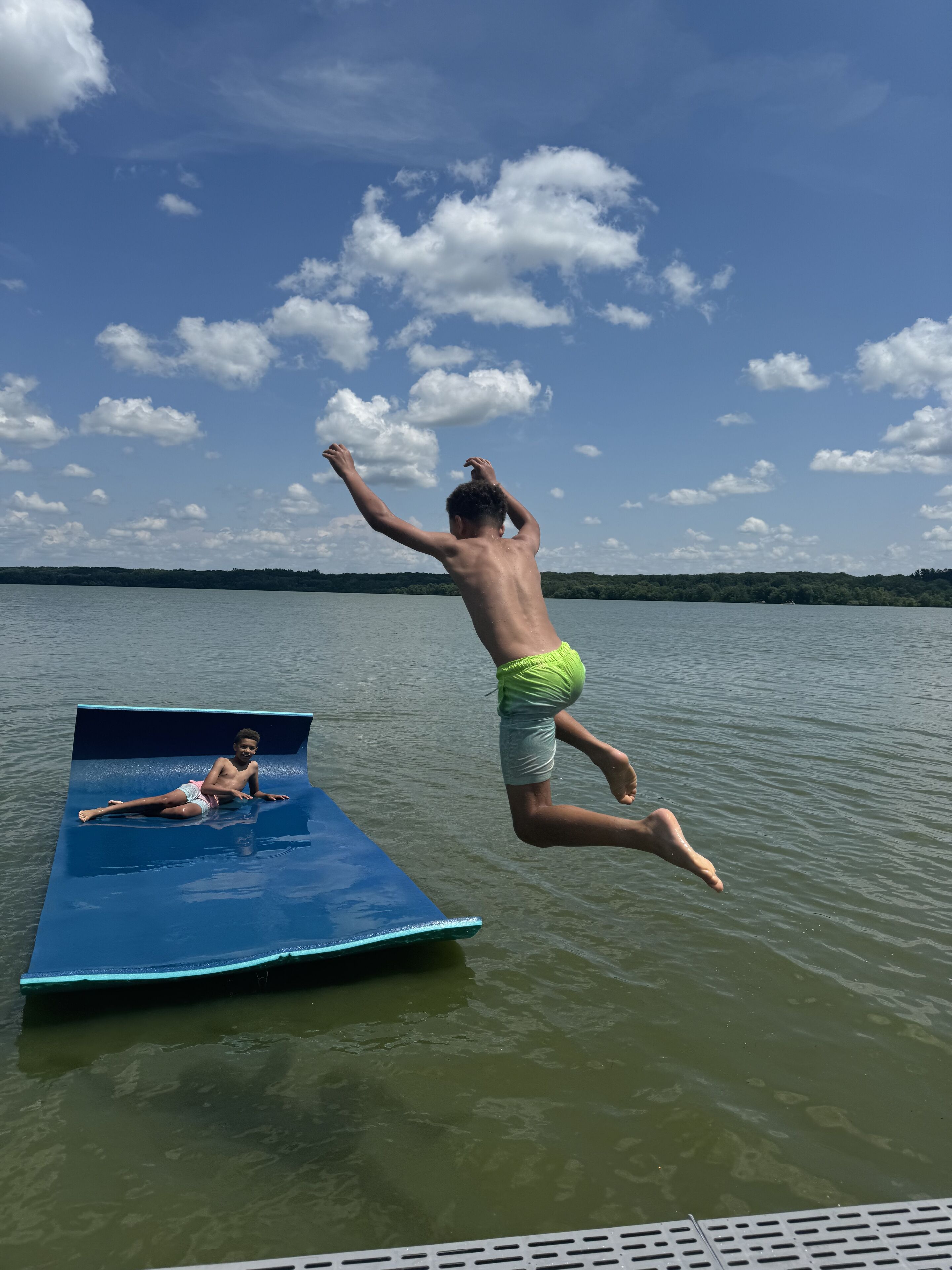 Une personne sautant d’une plateforme bleue pour plonger dans l’eau.