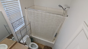 Een badkamer met douche, toilet en wastafel.