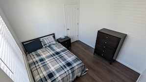 Een slaapkamer met een bed, een dressoir en een deur.