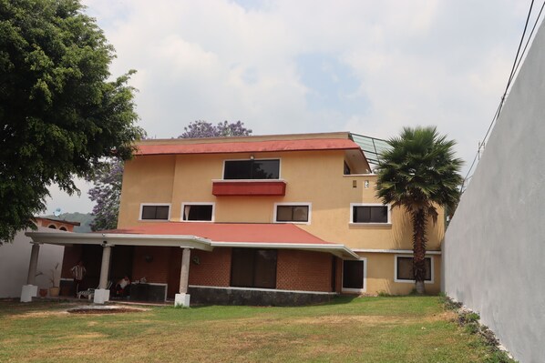 A two-story building with a red roof, a covered patio, and a palm tree in the yard.