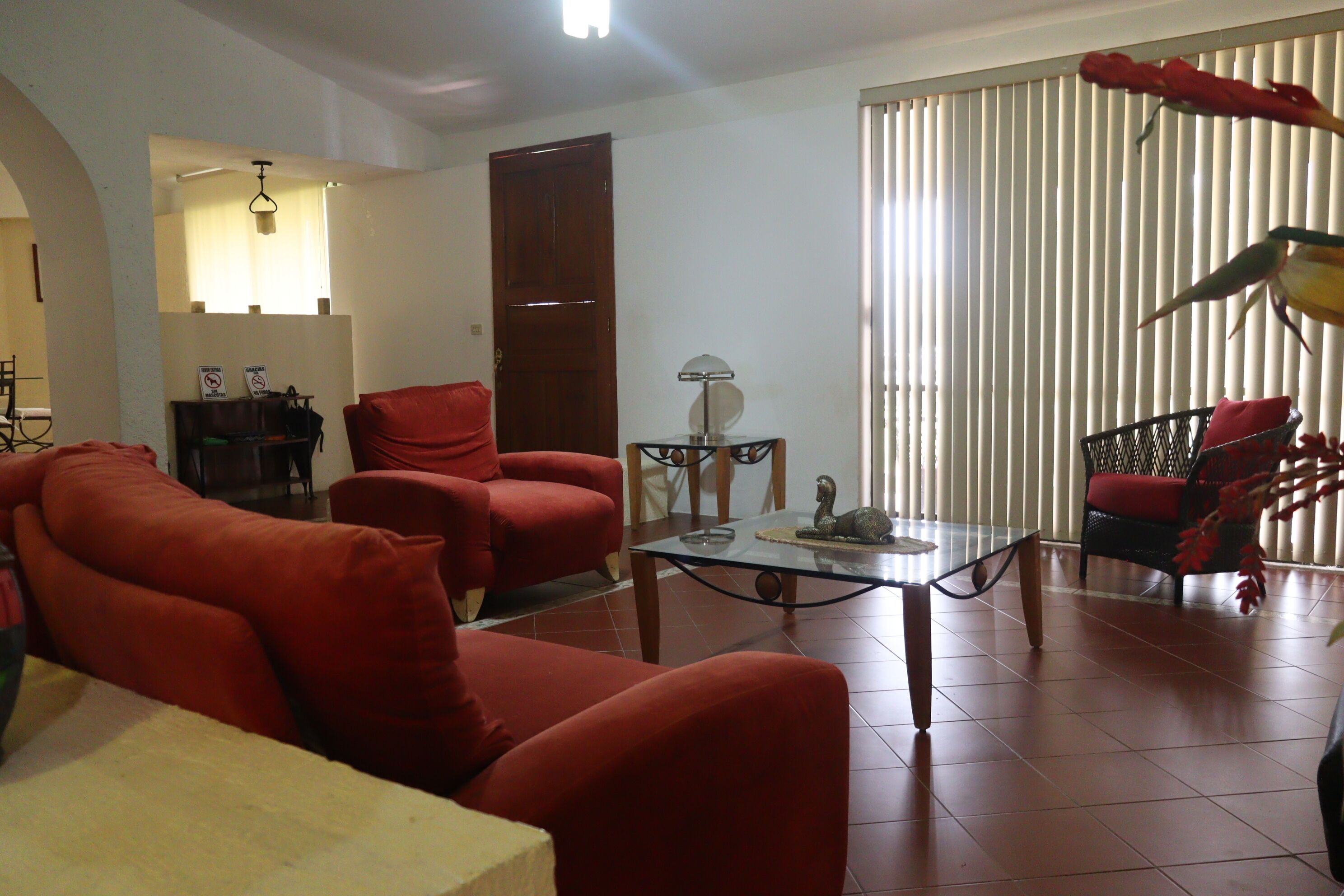 A living room with red sofas, a glass coffee table, and a decorative bird sculpture.