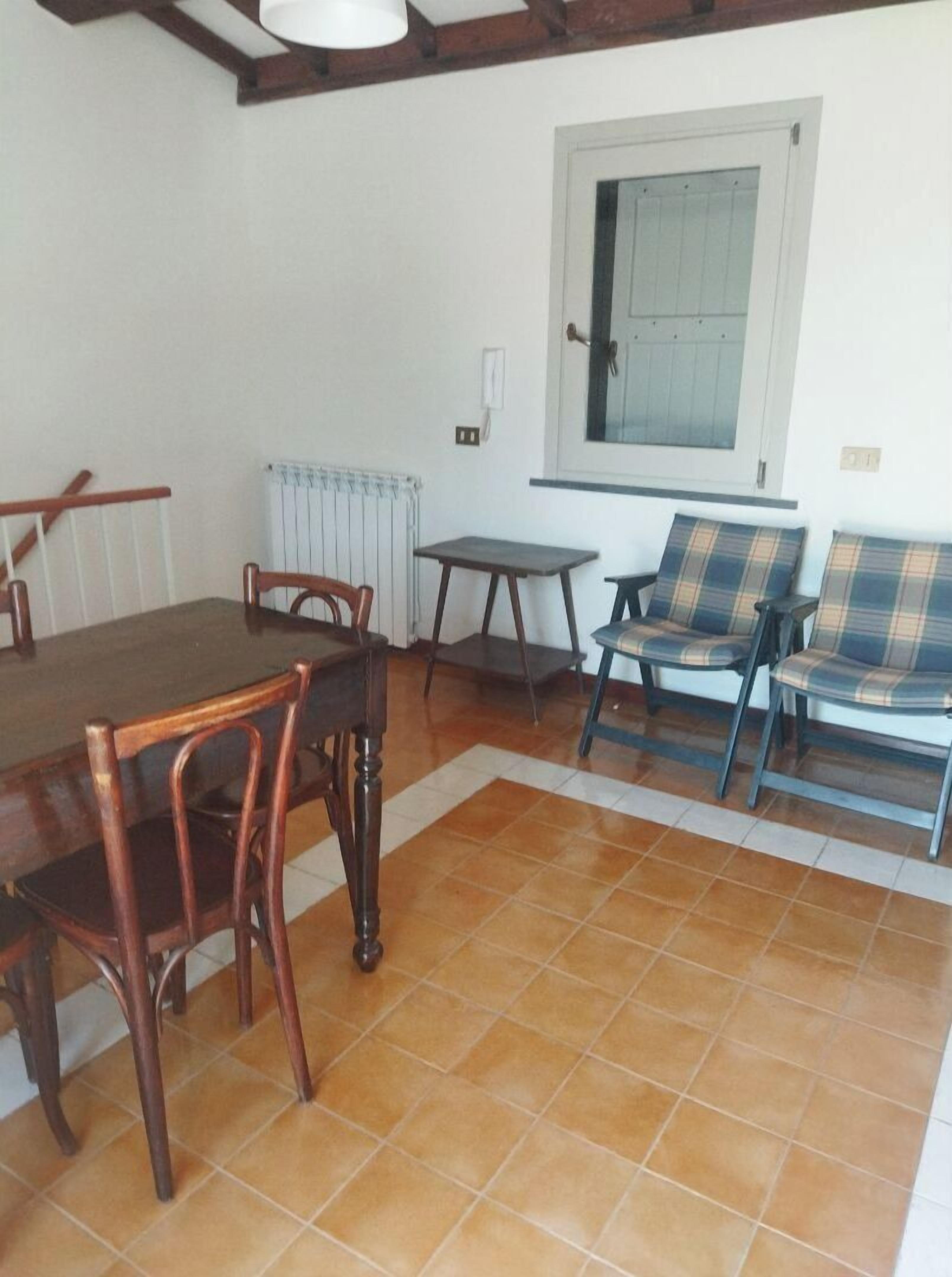 A dining area with a wooden table and chairs, a small table, and a window with a view.
