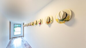 Un pasillo con varios sombreros colgados en la pared y una puerta que da a una habitación luminosa.