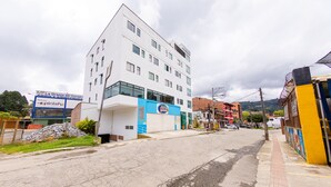 Un edificio de varios pisos con fachada azul y blanca, una entrada visible y un letrero que indica que es una obra en construcción.