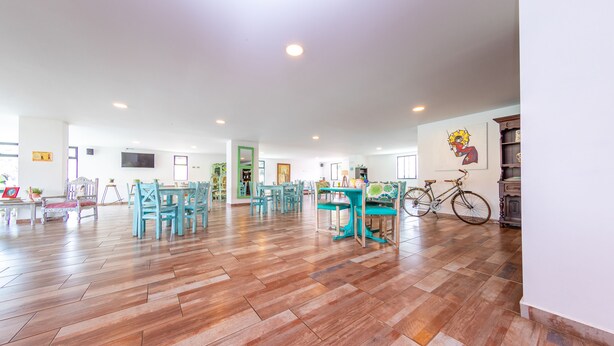 Una habitación amplia con piso de madera tipo espiga, sillas color turquesa y una bicicleta.