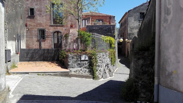 Un carrer empedrat estret, flanquejat per edificis històrics amb parets de pedra i reixes metàl·liques.