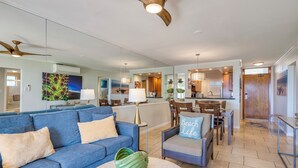 Een moderne woonkamer met een blauwe bank, een ronde salontafel, en een eethoek met een houten tafel en stoelen.