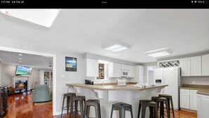 Een moderne keuken met een centraal eiland, barkrukken en een open haard.