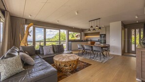 Uma sala de estar moderna com um sofá de couro, uma mesa de centro redonda de madeira e um espaço de jantar com mesa e cadeiras.