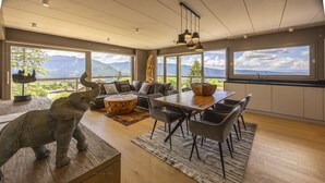 Uma sala de estar ampla, com mesa de jantar, assentos confortáveis e uma grande janela com vista para as montanhas.