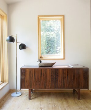 A wooden cabinet with a stone basin, a floor lamp, and a window with a view of trees. - Beautiful stream side cottage in the woods (Kerhonkson)