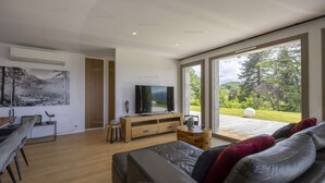 Un soggiorno moderno con un'ampia televisione a schermo piatto, un mobile TV in legno e un comodo divano con cuscini rossi.