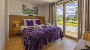 Camera da letto con un letto grande, un comodino, una lampada e vista su un giardino tramite una porta vetrata scorrevole.
