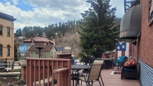 A wooden deck with outdoor furniture, a flag, and a brick wall. - The Stampmill Victorian Suites (Lead)