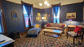 A room with a patterned carpet, a sofa, a chair, a table, and a lamp. - The Stampmill Victorian Suites (Lead)