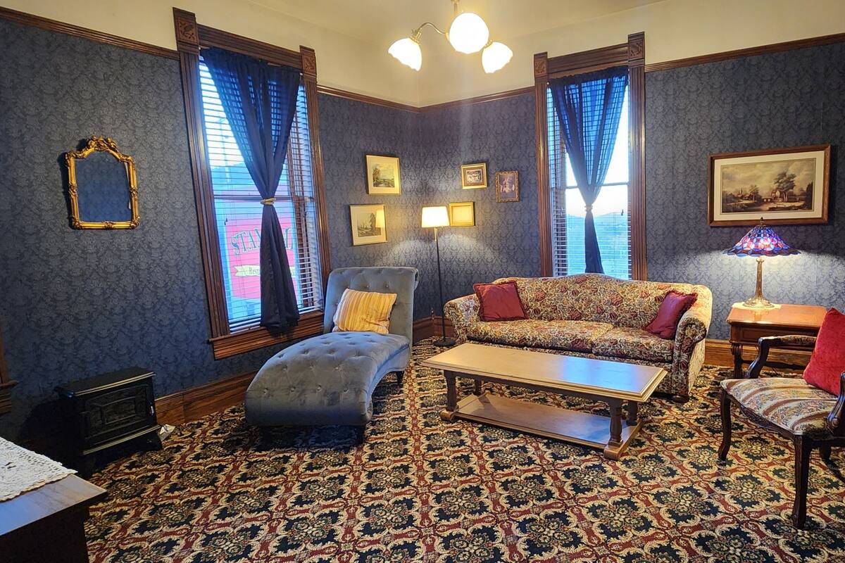 A room with a patterned carpet, a sofa, a chair, a table, and a lamp.