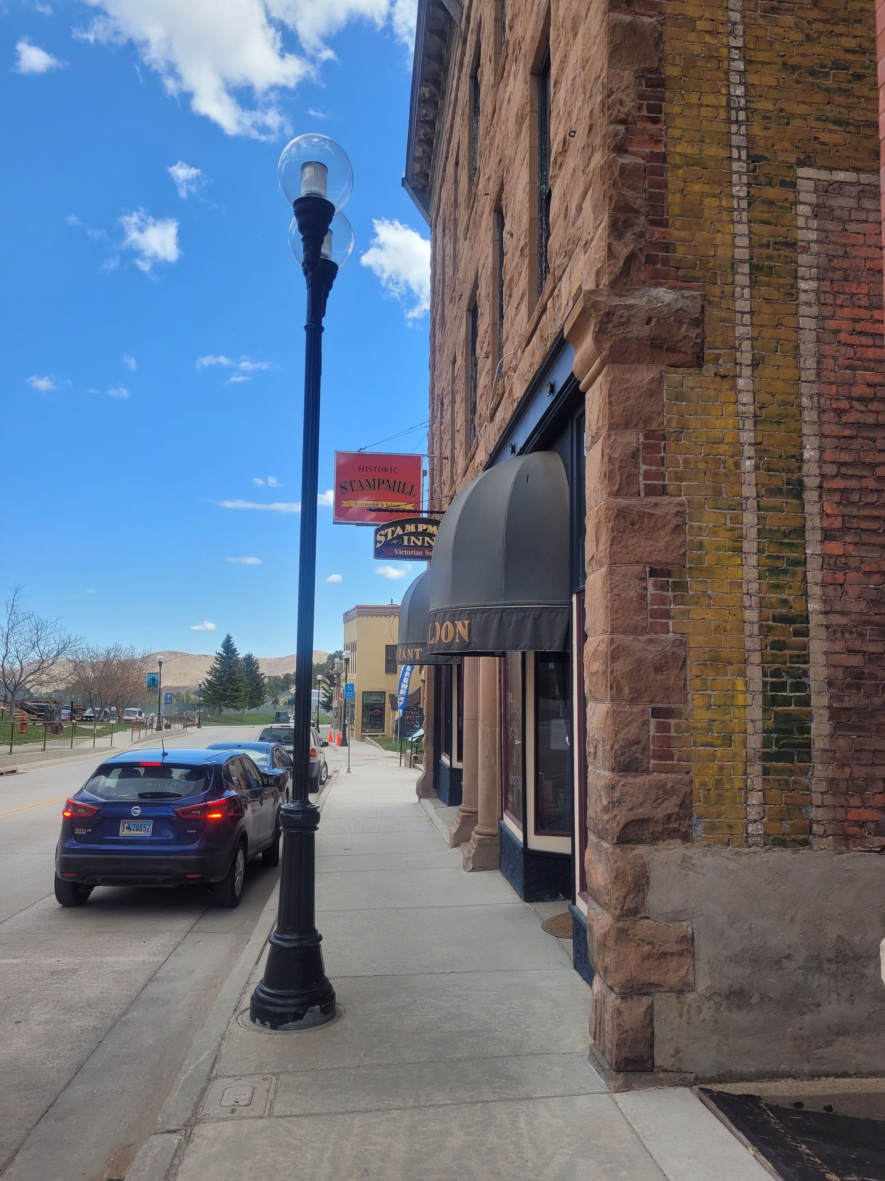 A historic building with a Victorian-style sign, a street lamp, and parked cars along the sidewalk.