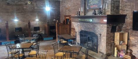 Interior de restaurante con paredes de ladrillo, mesas y sillas de madera.